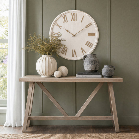 Wooden console table with decorative items against a green wall with a large clock.