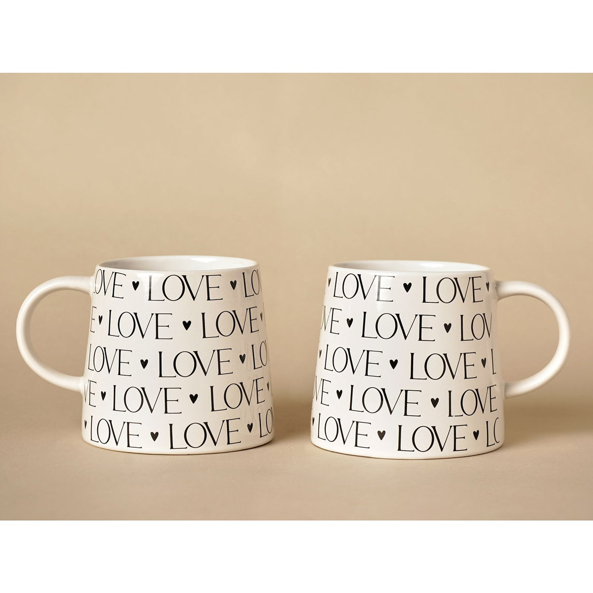 Two white mugs with 'LOVE' text on a beige background