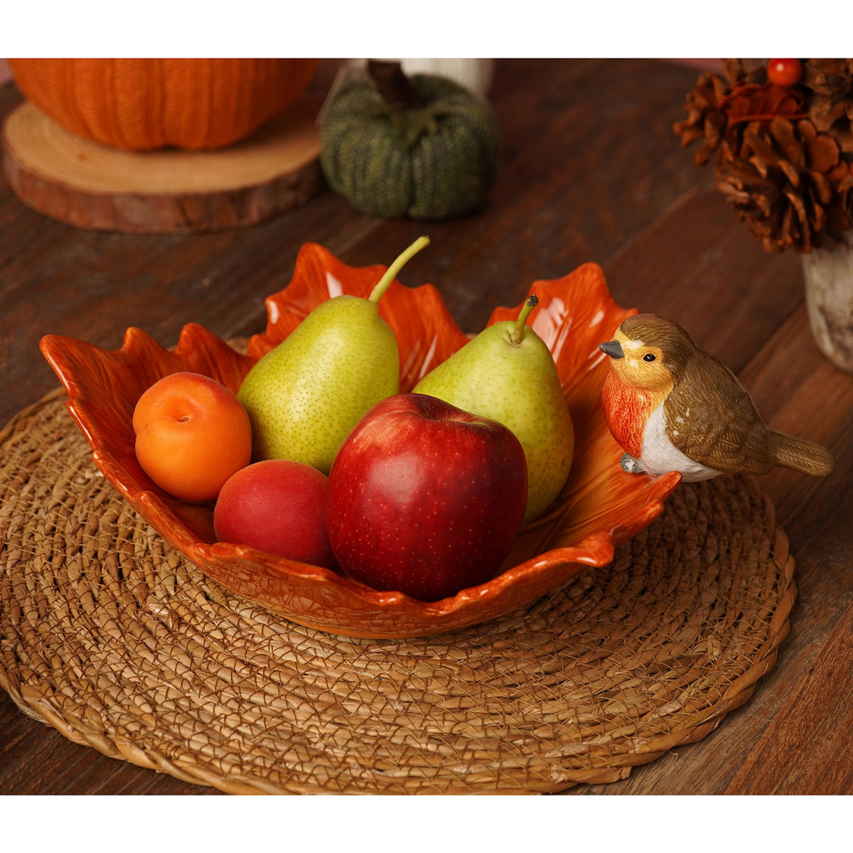 Decorative bowl with fruits and a bird figurine on a wooden surface