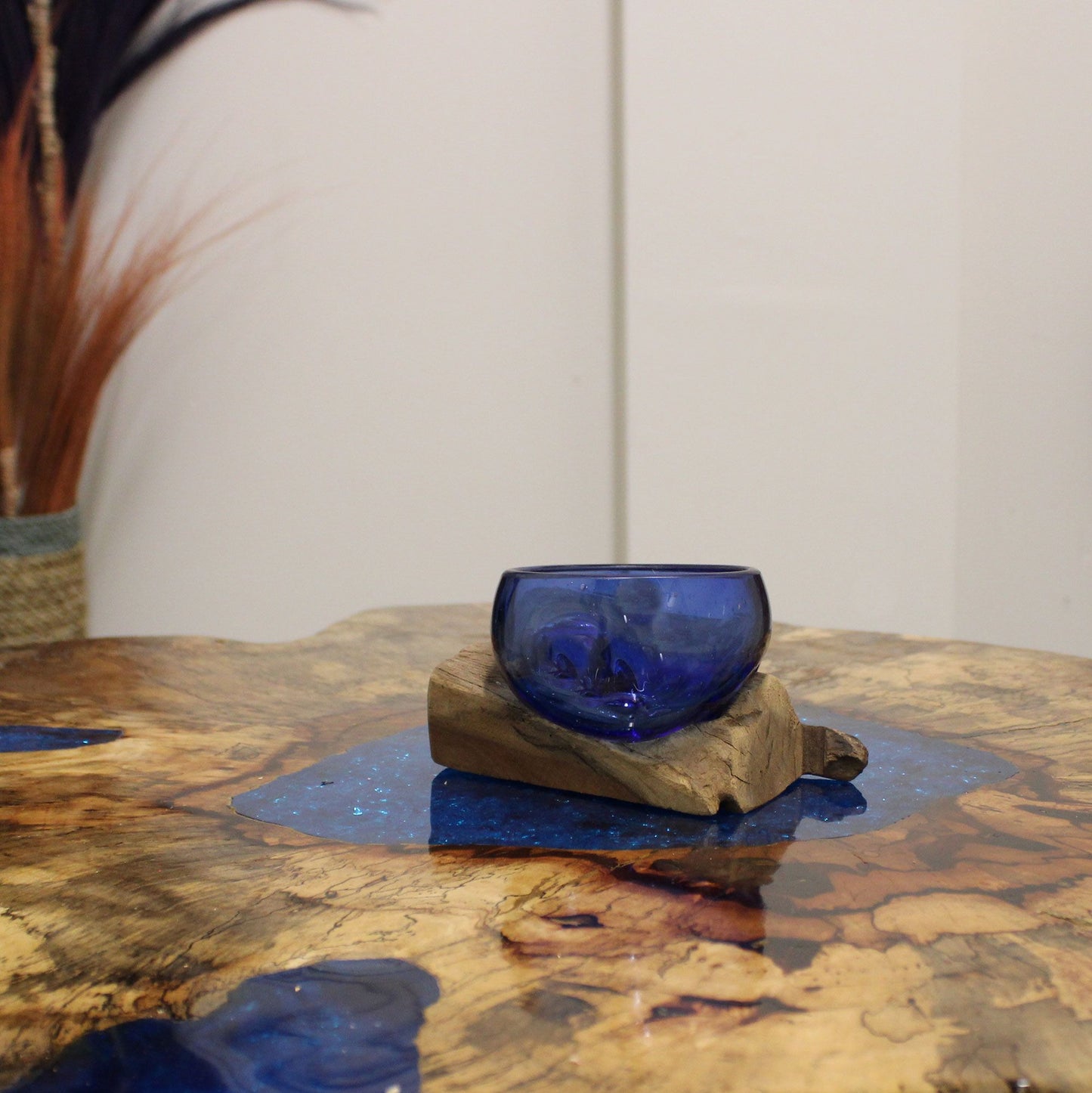 Blue glass bowl on a wooden stand with a blurred background